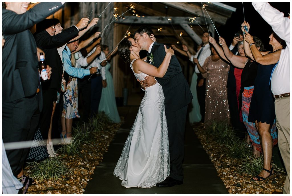 couple kissing under sparklers during wedding reception exit