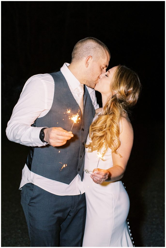 Sparkler exit photo of the bride and groom sharing a kiss.