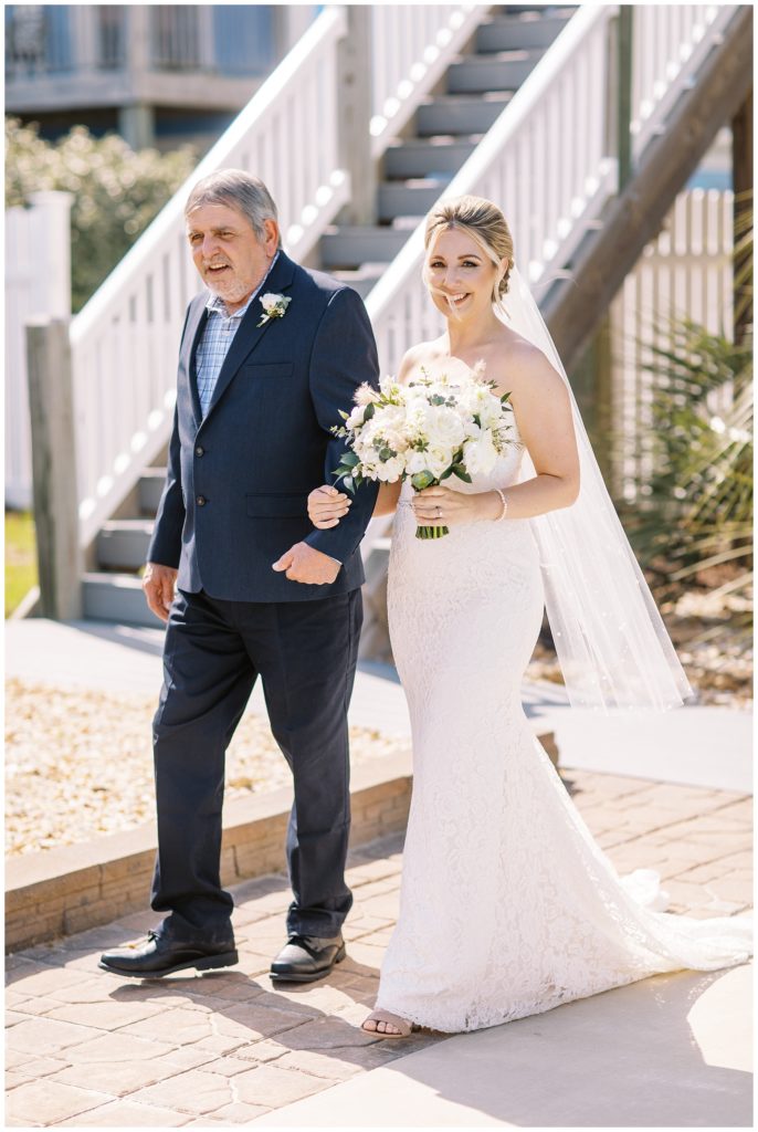 The bride walks down the aisle escorted by her father.