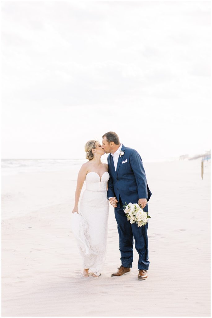The bride and groom walking together along the beach after their Topsail Beach wedding.