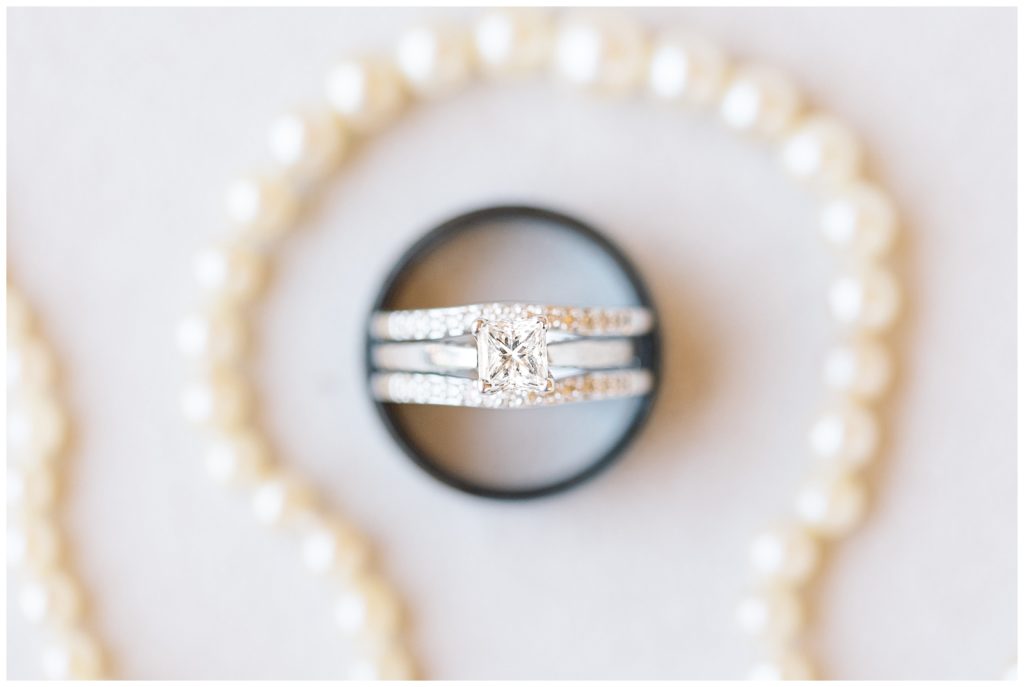 The brides rings and groom's wedding band surrounded by her grandmother's pearls.