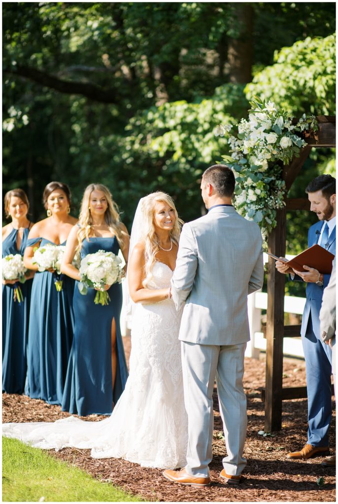 The bride reads her vows to her groom during their outdoor summer ceremony in Raleigh, NC.