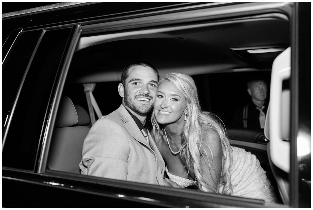 Black and white photo of the bride and groom in the car heading to their honeymoon.