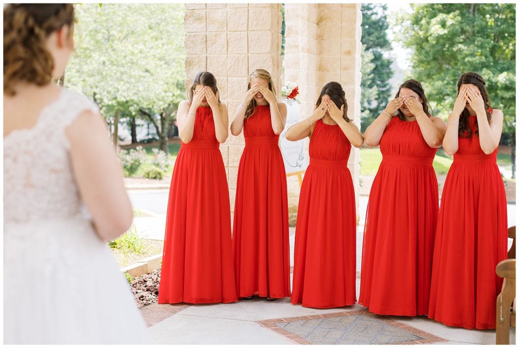 The bridesmaids cover their eyes in anticipation before seeing the bride for the first time!