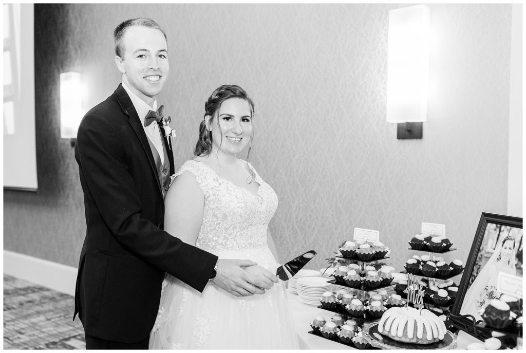 A black and white photo of the bride and groom cutting their wedding cake.