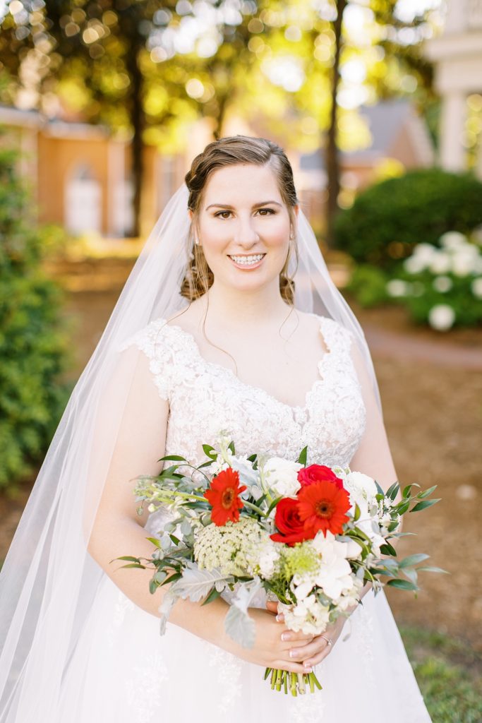 Outdoor bridal portraits in Holly Springs with red flowers.