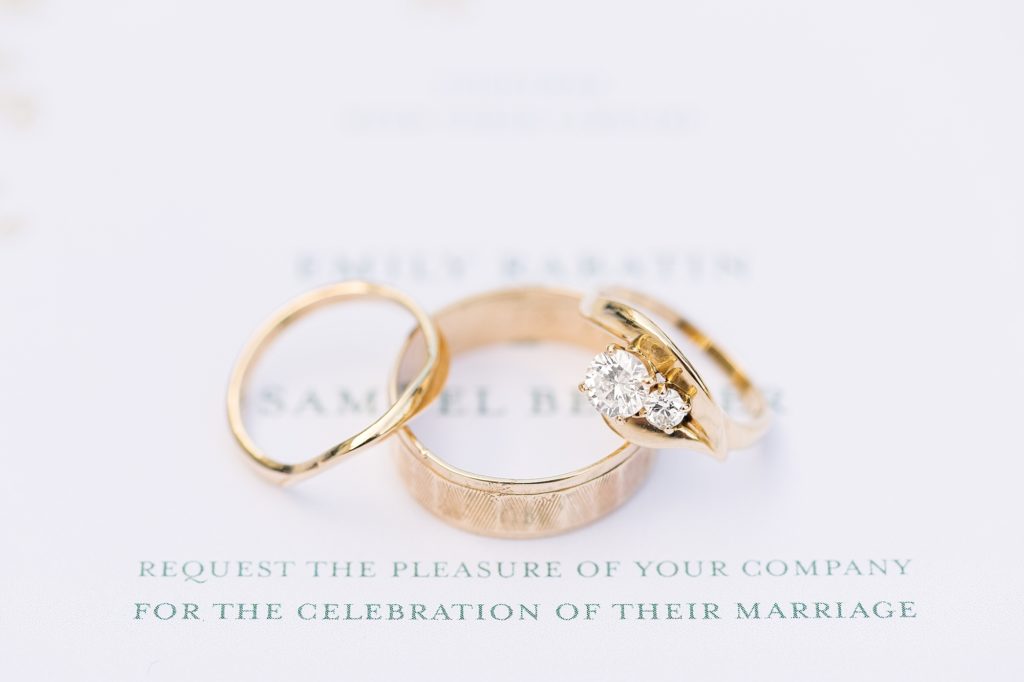 Gold wedding rings laying on top the wedding invitation | Raleigh Wedding Photographer