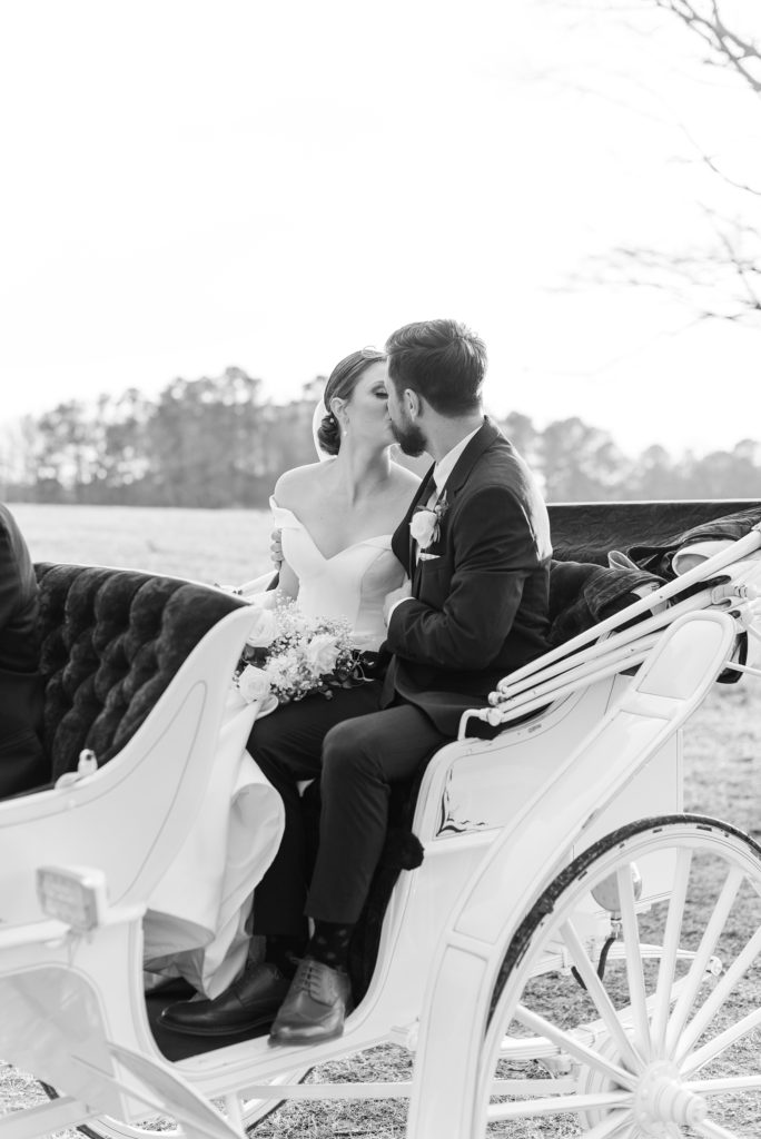 The bride and groom share a kiss in their horse carriage | Raleigh Wedding Photographer
