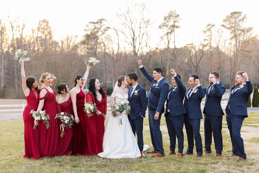 The wedding party cheers as the bride and groom kiss | Raleigh Wedding Photographer