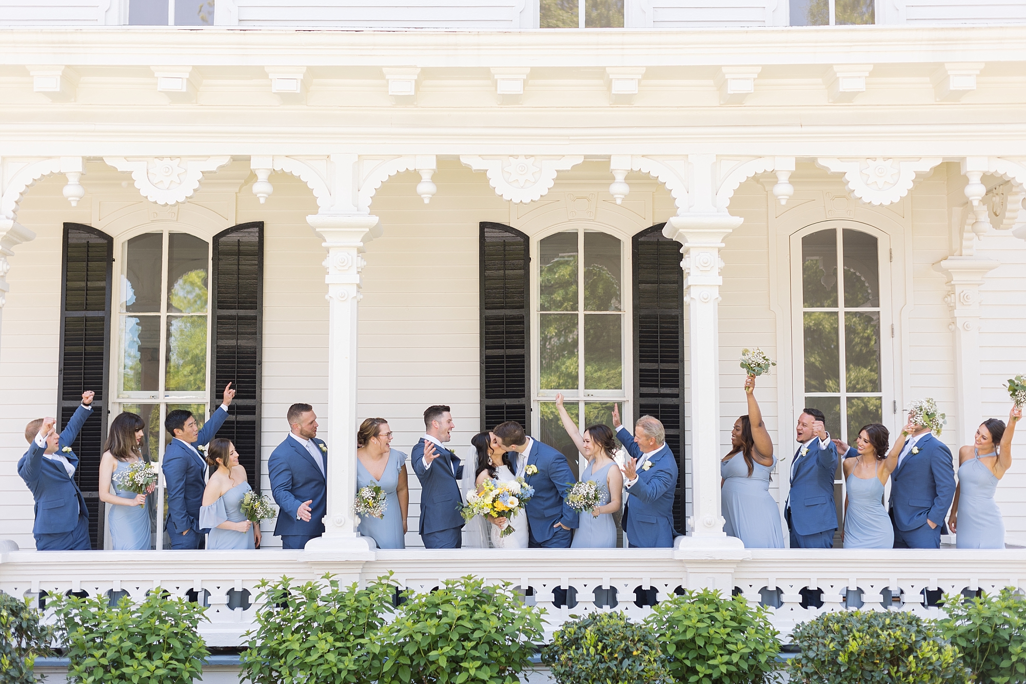 Bride and groom kissing with bridal party celebrating | Raleigh NC Wedding Photographer