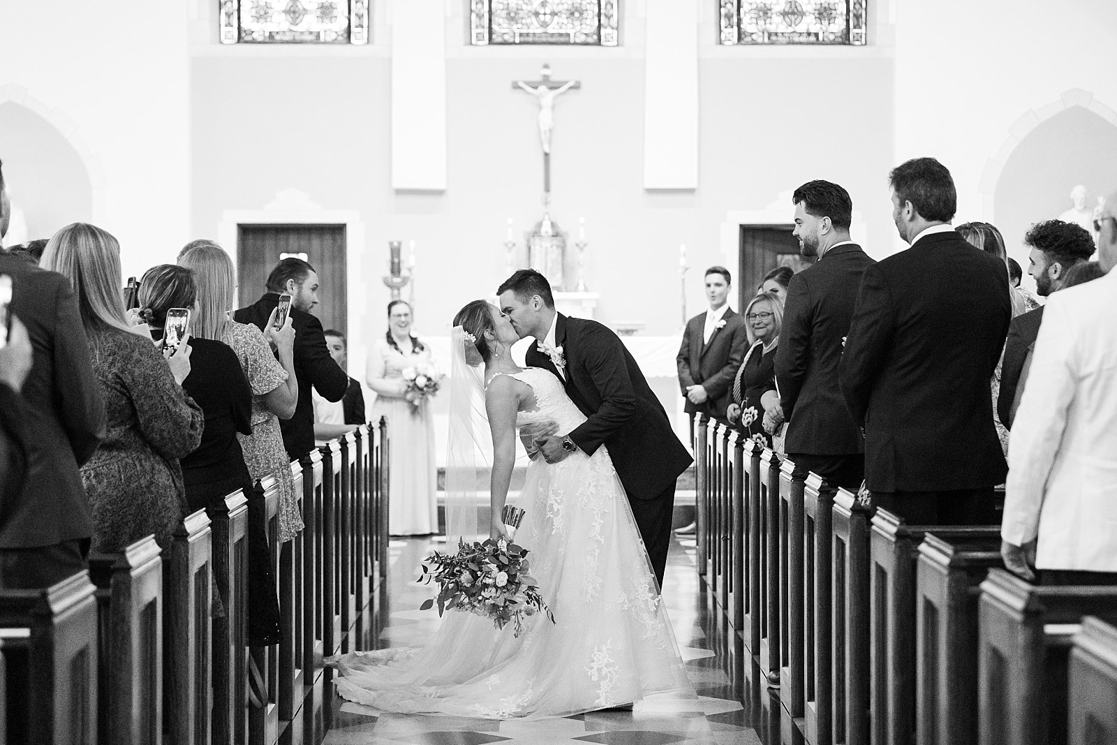 Black and white of bride and groom kissing down the aisle | Raleigh Wedding Photographer Sarah Hinckley