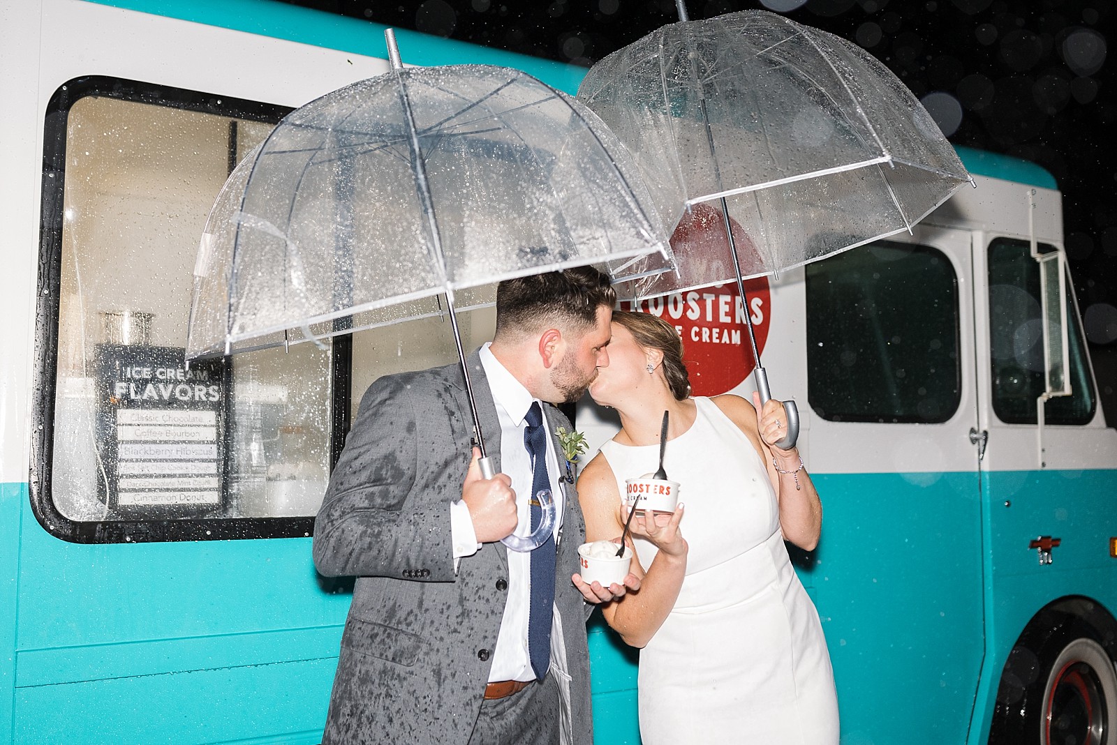 brie and groom kissing under umbrella with ice cream at their wedding during a hurricane bride and groom entering reception at The Upchurch in Cary NC | Raleigh NC Wedding Photography | Sarah Hinckley Photography