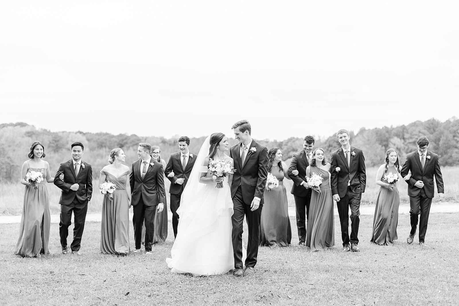 black and white photo of bridal party walking   | Fall Wedding at The Meadows in Raleigh | Raleigh NC Wedding Photographer