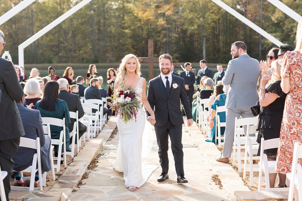 bride and groom hand in hand walking down the aisle | Fall wedding at Walnut Hill in Raleigh NC | Raleigh NC wedding photographer 