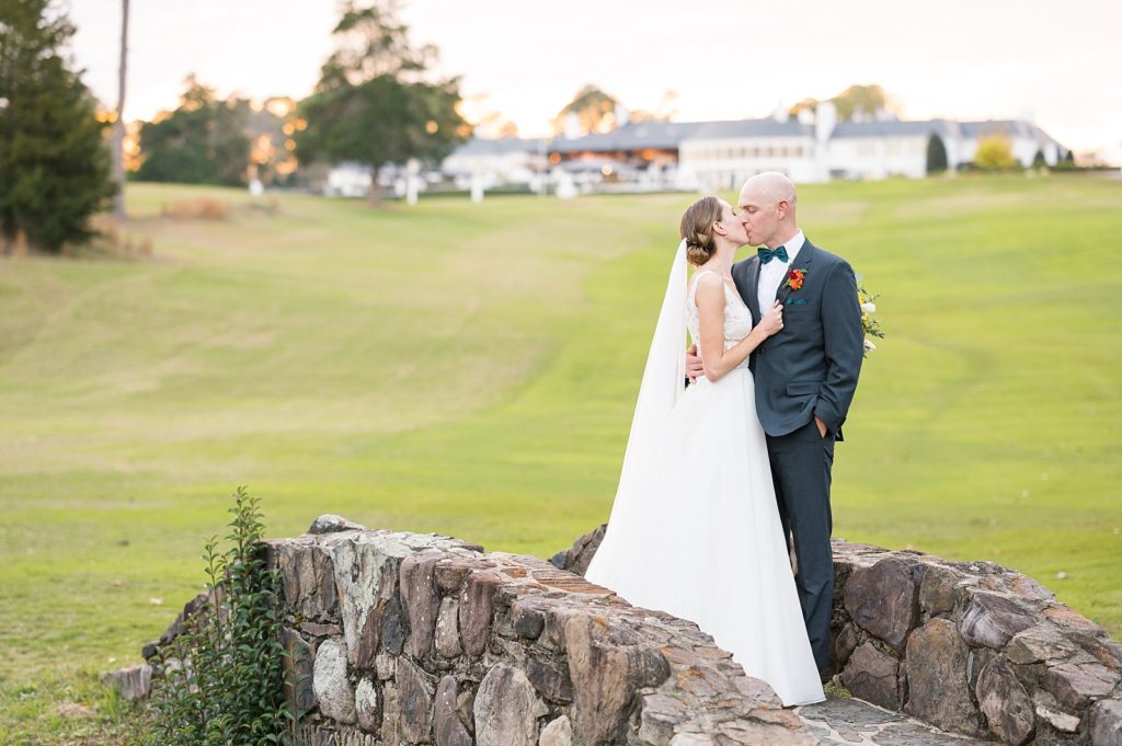 bride and groom kissing on stone bridge | Hope Valley Country Club | Durham Wedding | Raleigh NC wedding photographer 