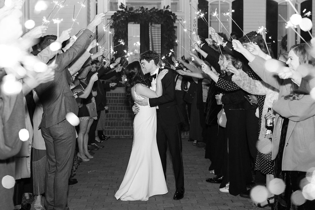 Black and white of bride and groom kissing during their sparkler exit  | Classic Black and white wedding at Merrimon-Wynne | Raleigh NC Wedding Photographer 
