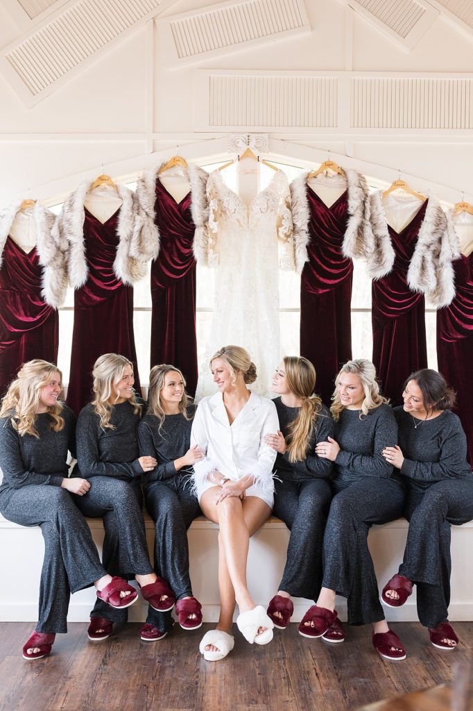 Bride with her bridesmaids in their pjs wearing fuzzy maroon slippers | Christmas Wedding at Pinehill Pavilion | Raleigh NC Wedding Photographer 