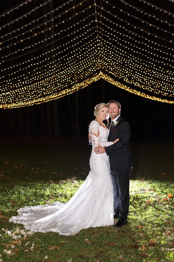 bride and groom under canopy lights | Christmas Wedding at Pinehill Pavilion | Raleigh NC Wedding Photographer 