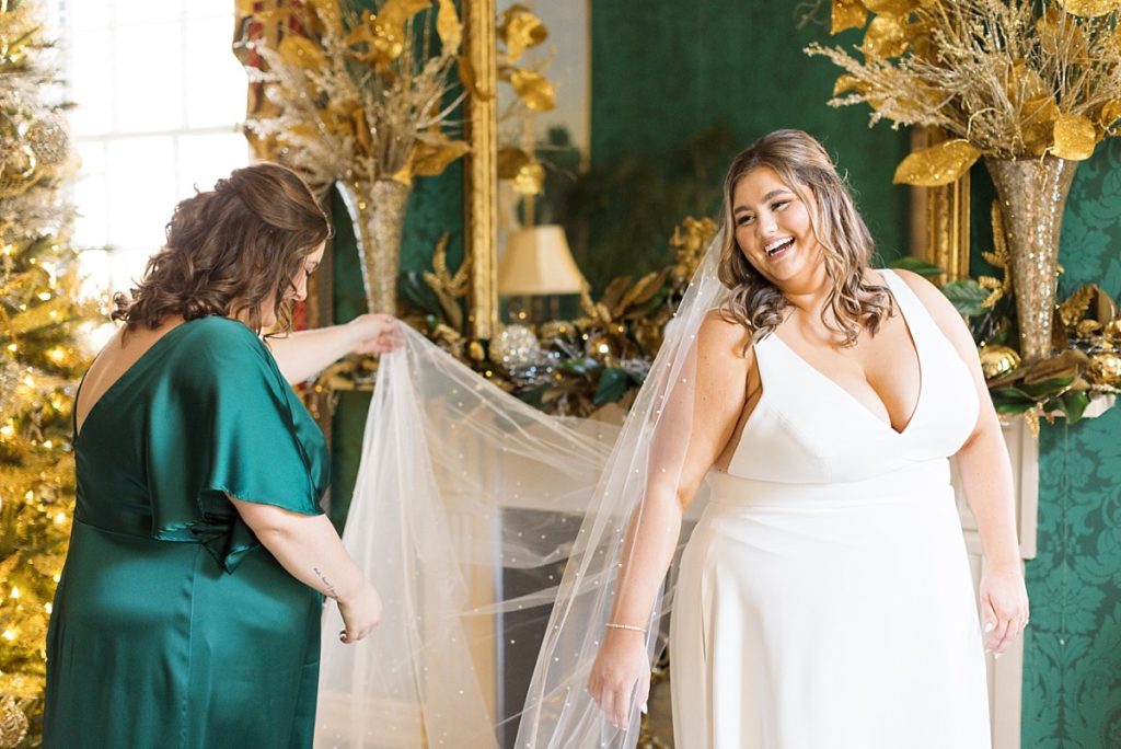 Bride with her maid of honor lifting her veil | Emerald Christmas Wedding at The Sutherland Estate | Raleigh NC Wedding Photographer