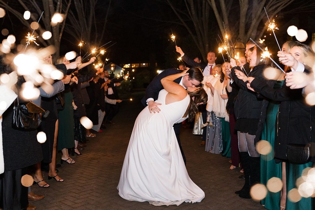 bride and groom kissing during their sparkler exit  | Emerald Christmas Wedding at The Sutherland Estate | Raleigh NC Wedding Photographe
