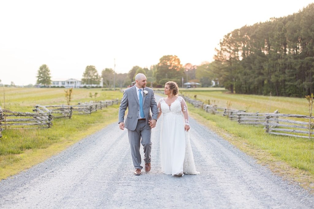 Spring bride and groom walking down fence lined path |Raleigh NC wedding photographer 