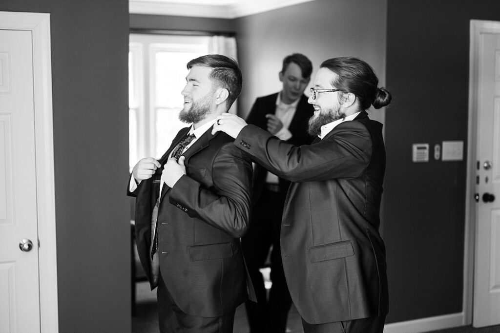 Groomsmen assisting groom with his jacket | Raleigh NC Wedding Photographer