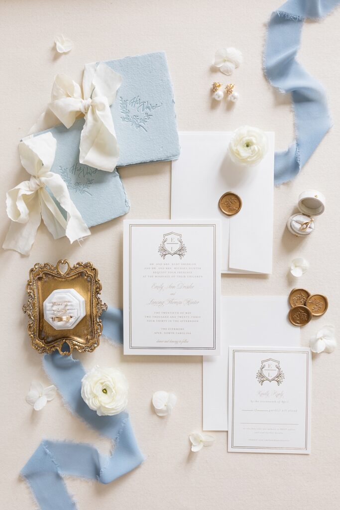 Wedding invitations displayed with blue and white ribbon and wedding rings displayed on antique tray | The Evermore Wedding | The Evermore Wedding Photographer | Raleigh NC Wedding Photographer