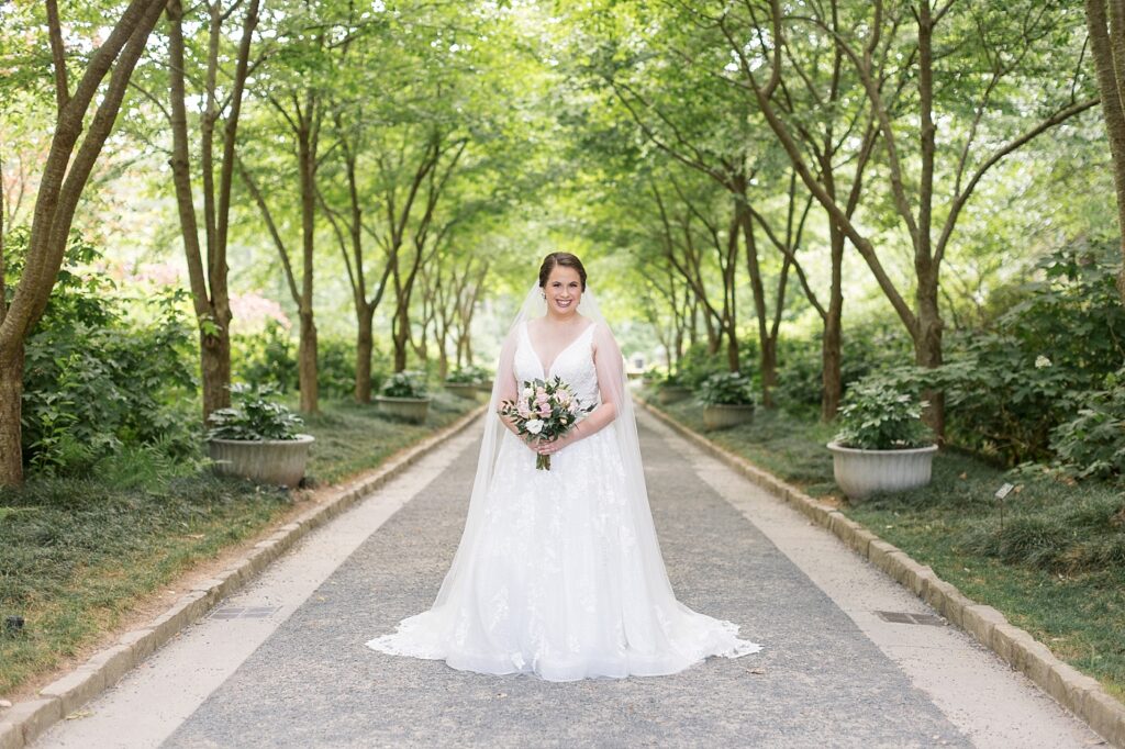 Bride holding bouquet outside under tree arch | Bridal Portraits at Duke Gardens | Raleigh NC Wedding Photographer | Bridal Portrait Photographer
