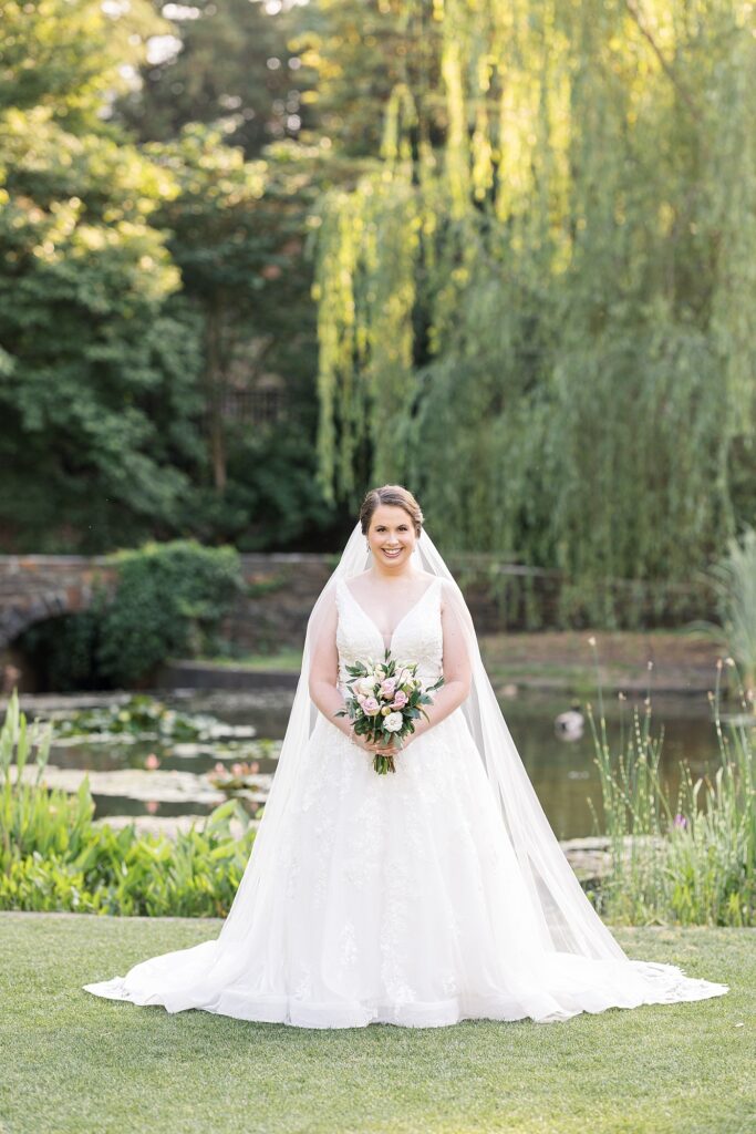 Bride posing near pond in garden holding bouquet | Bridal Portraits at Duke Gardens | Raleigh NC Wedding Photographer | Bridal Portrait Photographer