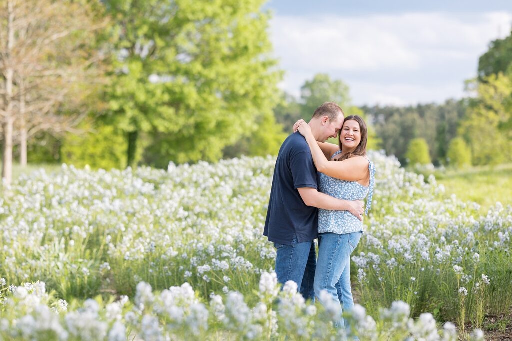 Couple embracing in garden with white flowers | Raleigh NC Engagement Photographer | Sarah Hinckley Wedding Photographer