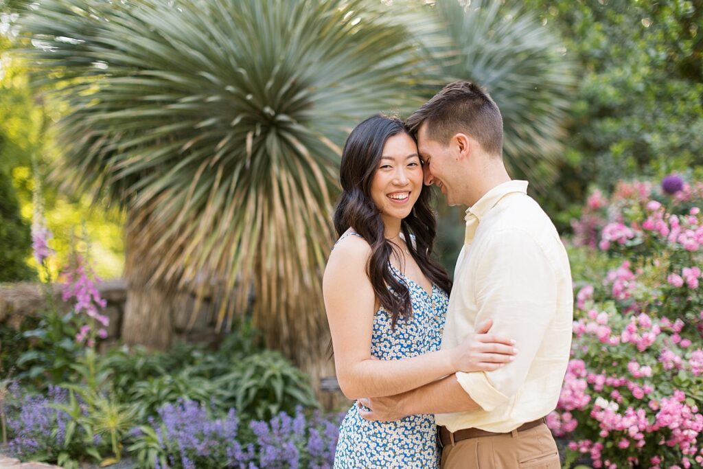 Couple embracing near pink and purple flowers in garden | Duke Gardens engagement photos | Raleigh NC wedding photographer 