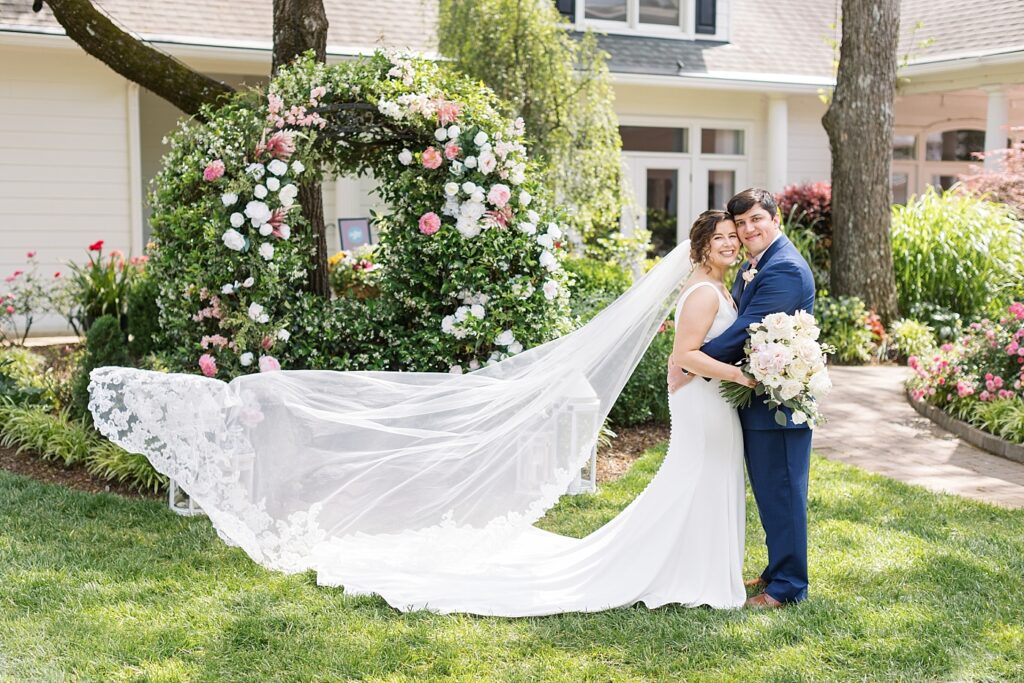 Bride and groom embracing in garden with pink and white roses | Spring Wedding | The Matthews House Wedding | The Matthews House Wedding Photographer | Raleigh NC Wedding Photographer