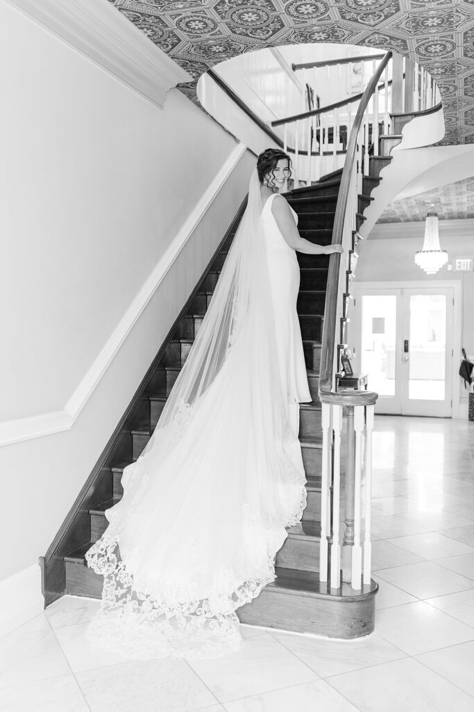 Bride standing on staircase showing wedding dress and veil | Spring Wedding | The Matthews House Wedding | The Matthews House Wedding Photographer | Raleigh NC Wedding Photographer