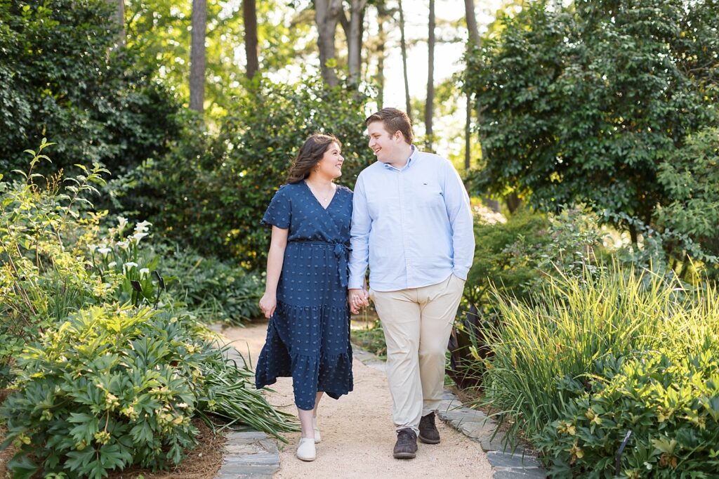 Couple holding hands and walking through garden | WRAL Gardens engagement photos | Raleigh NC wedding photographer 