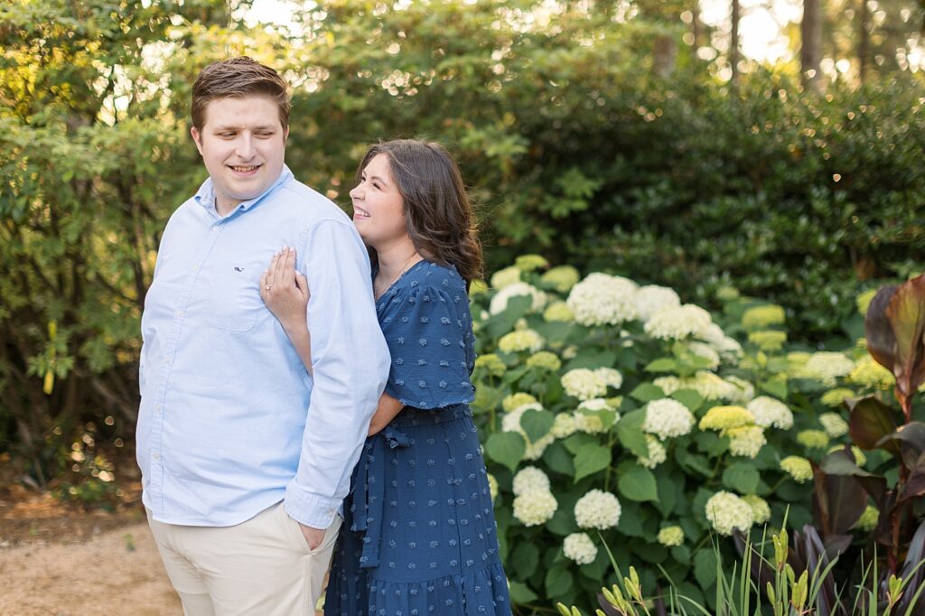 Couple embracing near white flowers in garden | WRAL Gardens engagement photos | Raleigh NC wedding photographer 