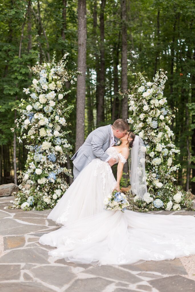 Bride and groom kissing in front of blue and white flowers | Blue and white Wedding | Carolina Groves Wedding | Carolina Groves Wedding Photographer | Raleigh NC Wedding Photographer
