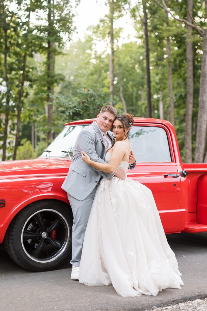 Bride and groom embracing by red vintage truck | Blue and white Wedding | Carolina Groves Wedding | Carolina Groves Wedding Photographer | Raleigh NC Wedding Photographer