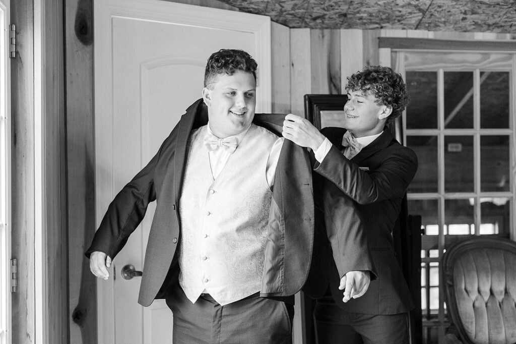 Groomsmen helping groom put on suit jacket | Rustic wedding | Harvest House Wedding | Harvest House Photographer | Raleigh NC Wedding Photographer