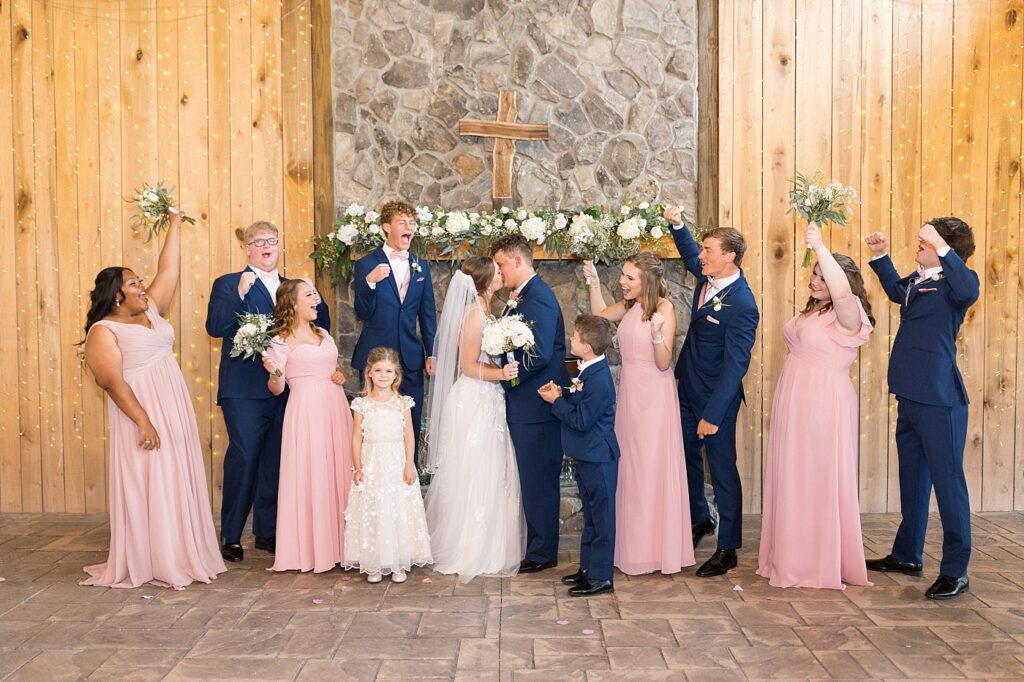Bride and groom kissing surrounded by wedding party cheering | Rustic wedding | Harvest House Wedding | Harvest House Photographer | Raleigh NC Wedding Photographer