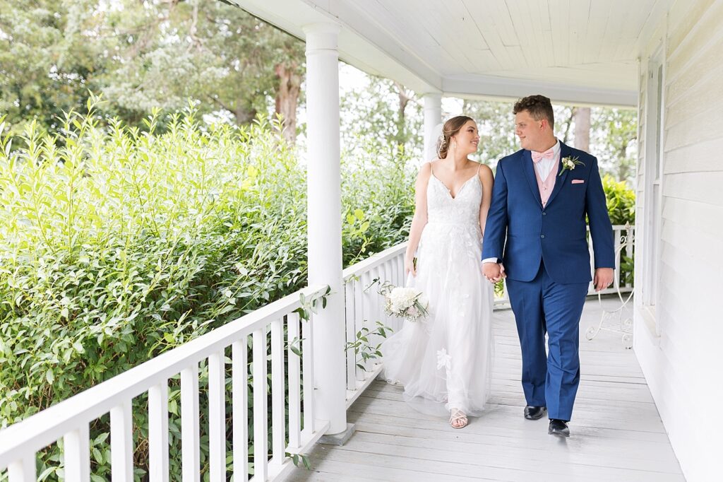 Bride and groom holding hands and walking on venue porch | Rustic wedding | Harvest House Wedding | Harvest House Photographer | Raleigh NC Wedding Photographer