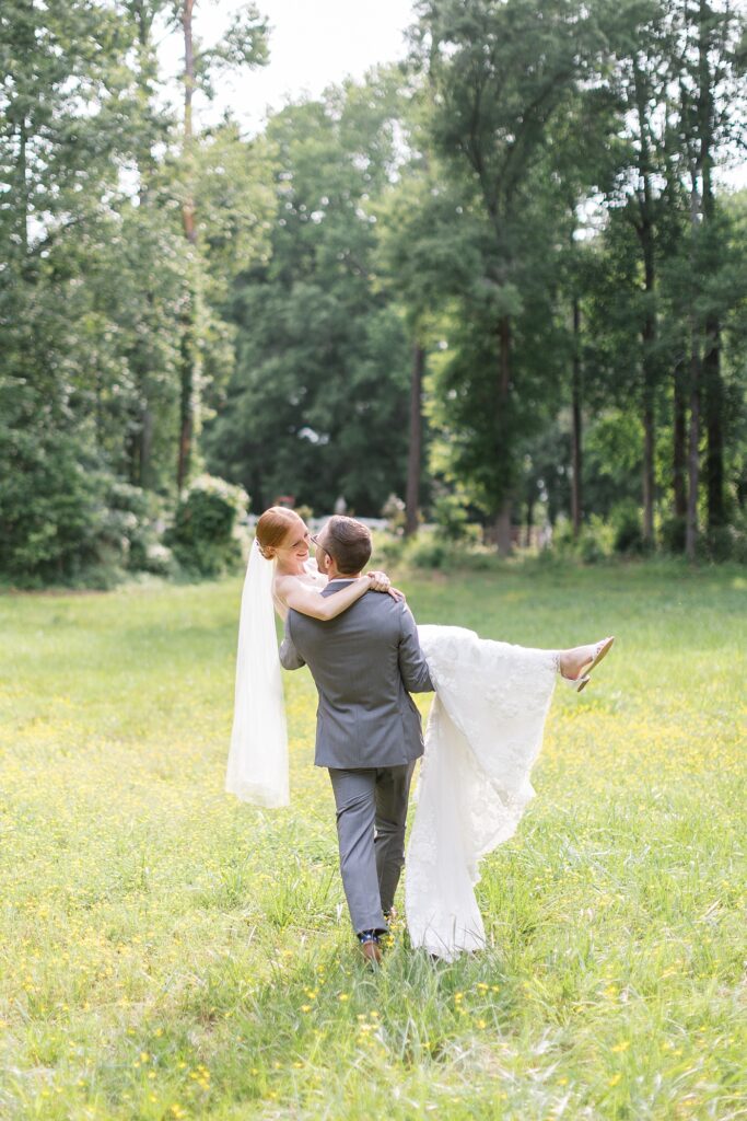 Groom carrying bride through open field | Rustic Wedding | Twin Oaks Barn Wedding | Twin Oaks Barn Wedding Photographer | Raleigh NC Wedding Photographer
