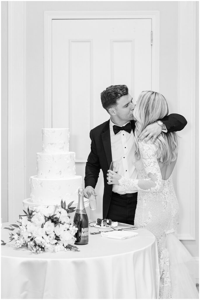 Bride and groom kissing by wedding cake | Classic Summer Wedding | Wedding with Neutrals | Carolina Inn Wedding on The Lawn | UNC Alumni Wedding | Raleigh Wedding Photographer | NC Wedding Photographer