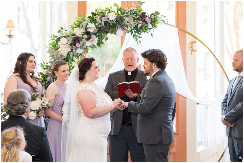 Bride placing wedding ring on groom's finger during wedding ceremony | Caffe Luna Wedding | Caffe Luna Wedding Photographer | Raleigh NC Wedding Photographer