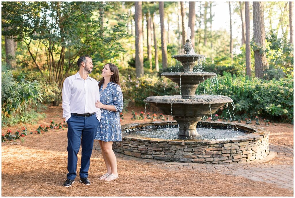Couple embracing by fountain in garden | WRAL Gardens engagement photos | Raleigh NC wedding photographer 