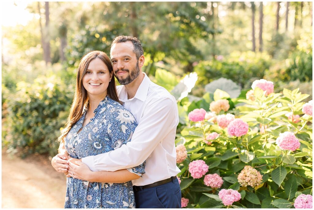 Couple embracing in pink azalea garden | WRAL Gardens engagement photos | Raleigh NC wedding photographer 
