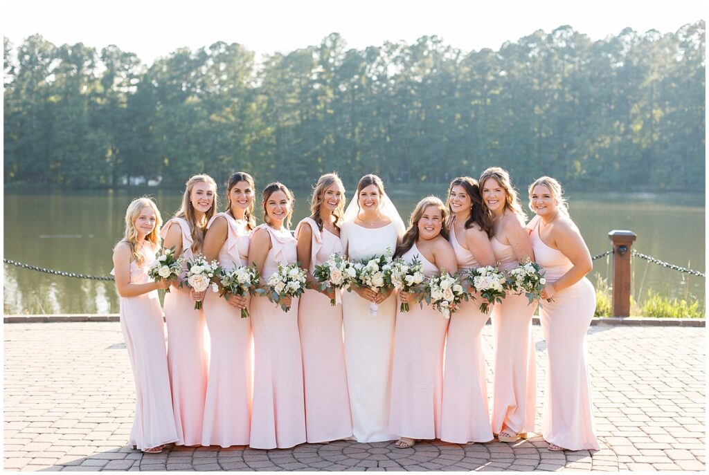 Bride and bridesmaids standing by lake | Summer Wedding | Angus Barn Wedding | Angus Barn Wedding Photographer | Raleigh NC Wedding Photographer