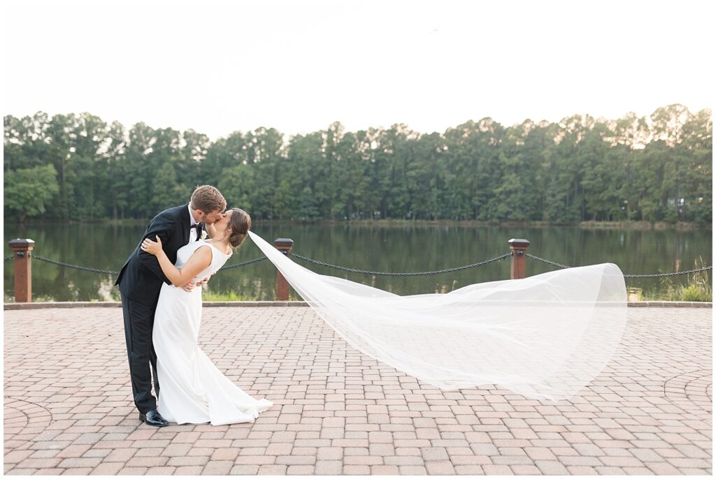 Bride and groom kissing by lake | Summer Wedding | Angus Barn Wedding | Angus Barn Wedding Photographer | Raleigh NC Wedding Photographer