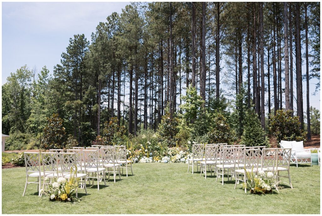 Wedding Ceremony on the lawn with white chairs and yellow florals | The Upchurch | Raleigh NC