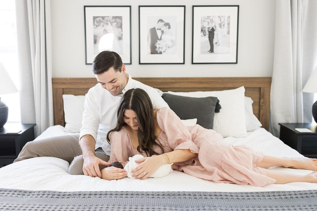 parents holding baby in bed | mom cuddling newborn baby in bed | newborn baby | newborn photography Raleigh NC | baby girl newborn session | lifestyle family photography